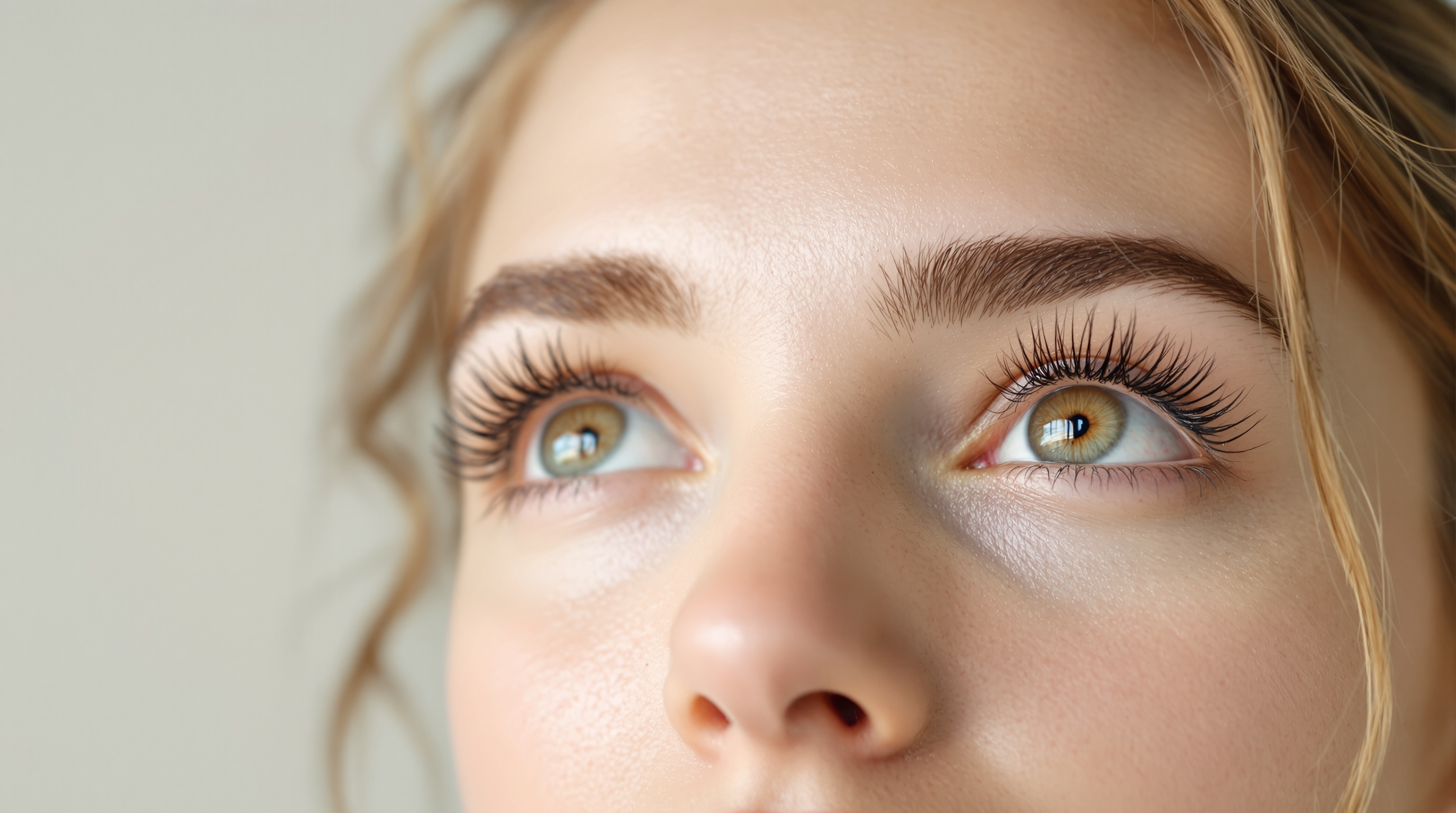 Gros plan sur les yeux d'une femme aux cils longs et maquillés, regardant vers le haut.